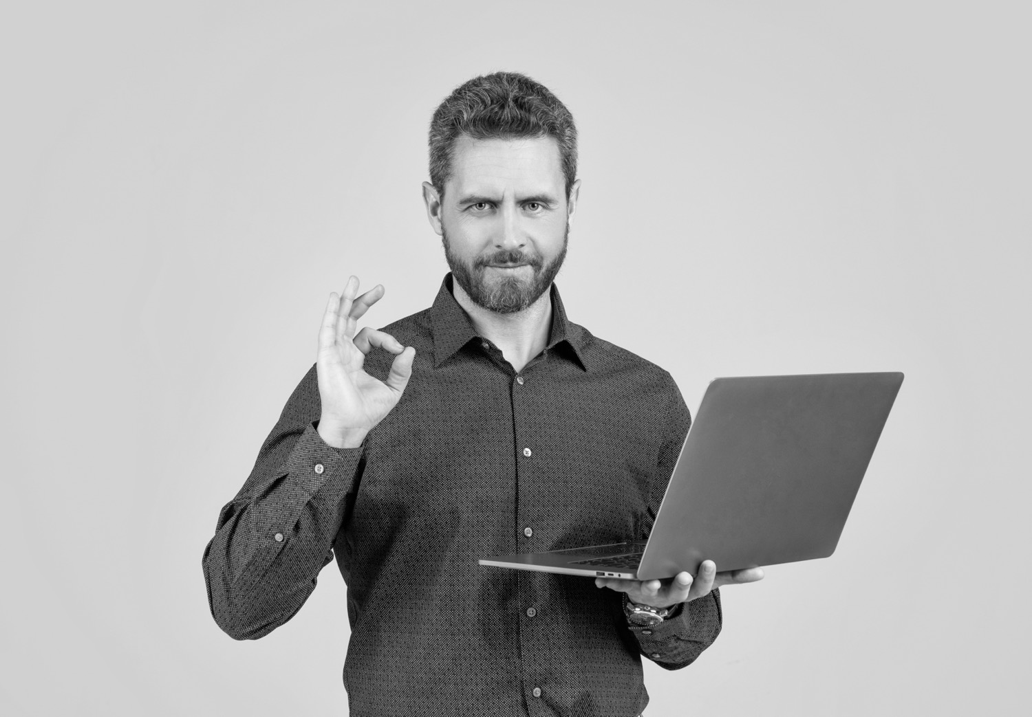computerprogrammierer zeigen ringgeste mit tragbarem laptop auf grauem hintergrund ok